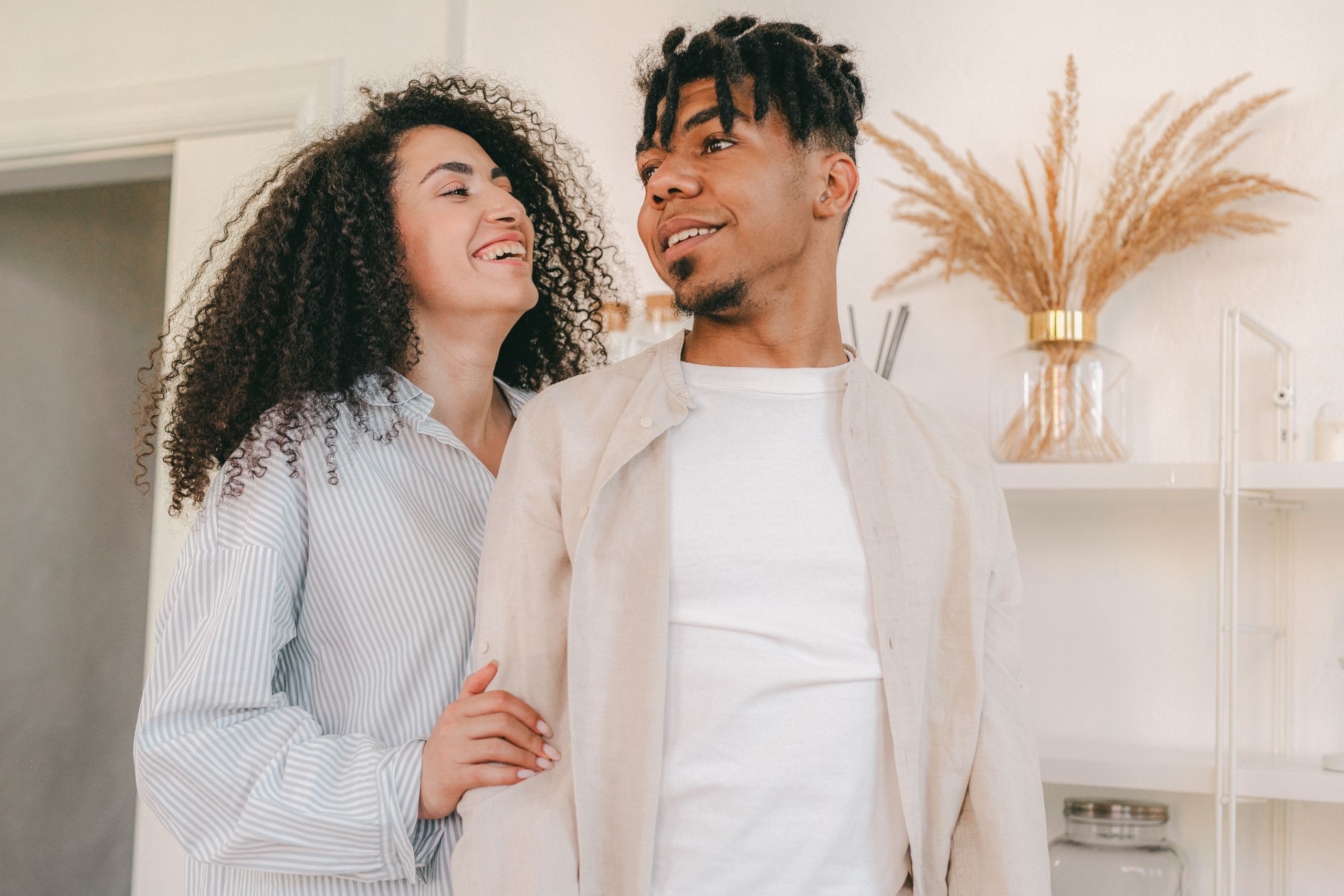 Smiling couple sharing a loving moment indoors with natural decor.