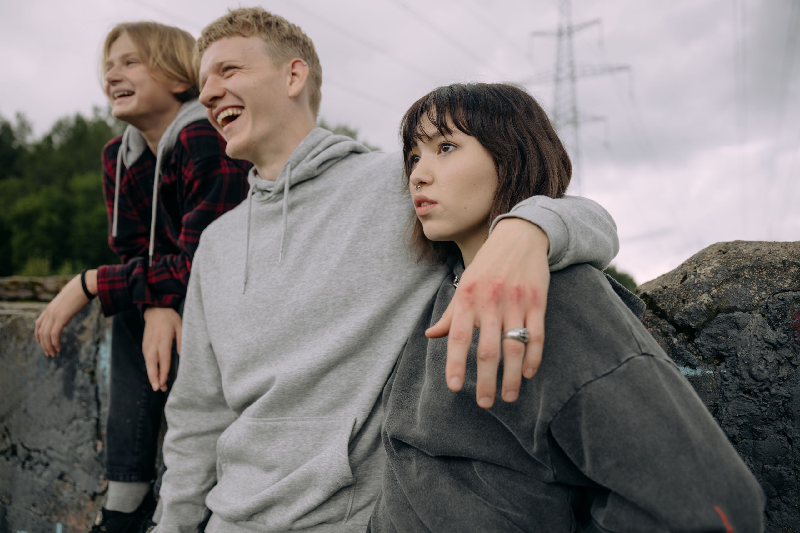 Three teenagers in casual wear enjoying a cheerful moment outdoors.
