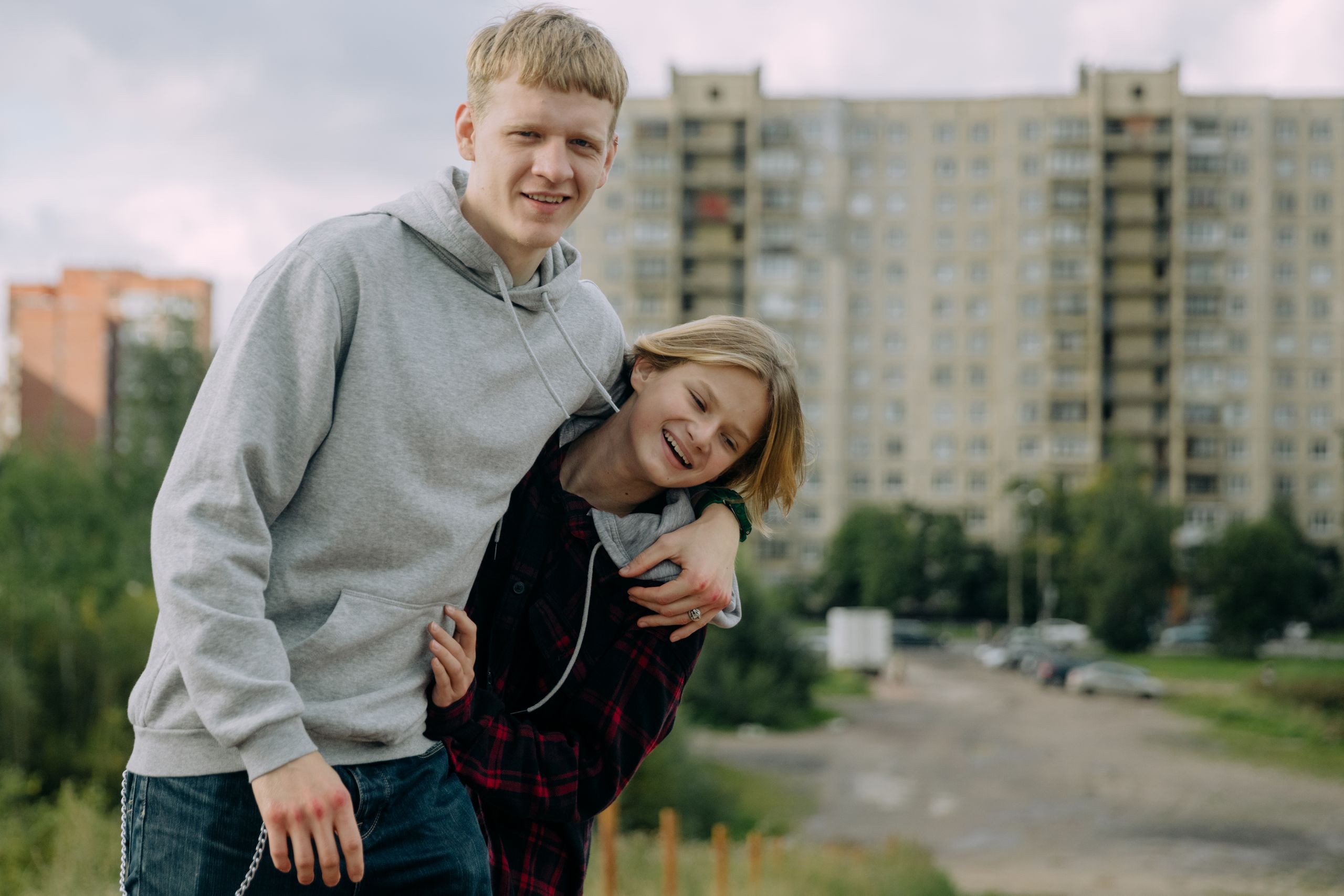 Two happy siblings bonding outdoors in a city setting.